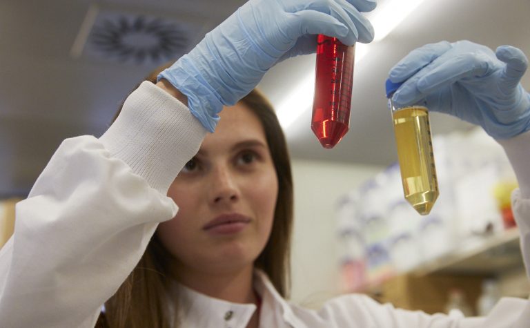 female researcher looking at liquids in tubes