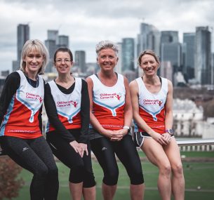 four marathon mums wearing vests smiling looking at camera sitting on metal handrail