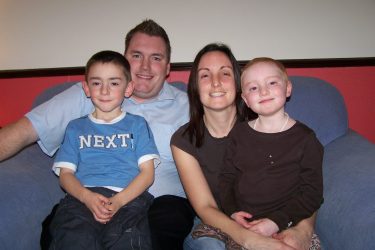 Bethan with family of mum dad and brother sitting on blue couch