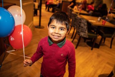 Boy with maroon jumper holding balloons min (1)