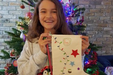Phoebe girl smiling holding a christmas white stocking