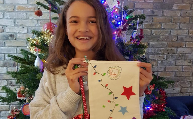 Phoebe girl smiling holding a christmas white stocking