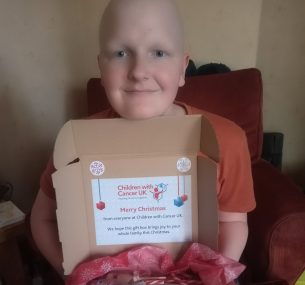 girl holding a christmas gift box smiling at camera