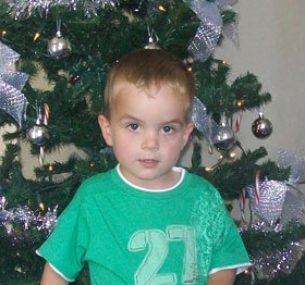 Harry with a green tshirt standing by a christmas tree holding teddy 1