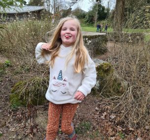 Daisy standing in front of a tree stump min