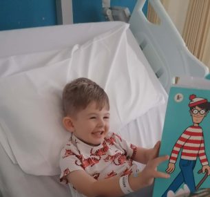 Finley in hospital bed readin wheres wally