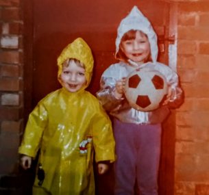 two boys looking at comera with christopher wearing yellow jacket and the other boy is wearing white hoodie