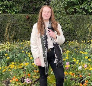 Ellen standing in a garden holding coffee cup min