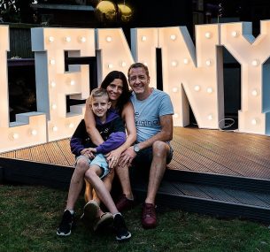 Lenny and his parents sitting witha big Lenny LED sign BEHIND THEM