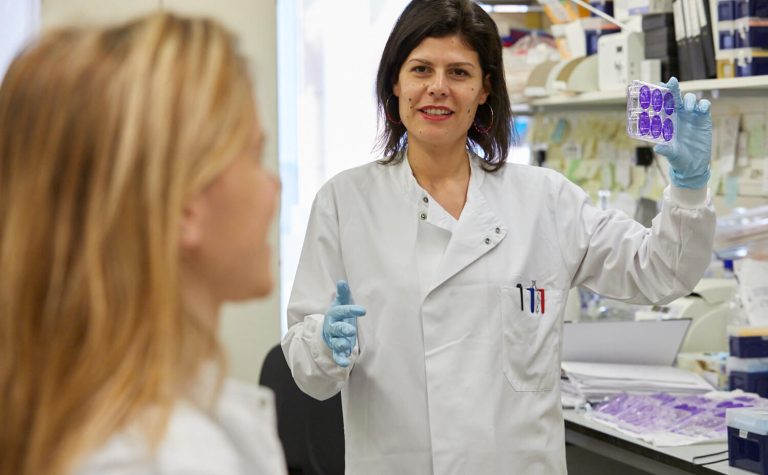 female researcher holding purple cell plate