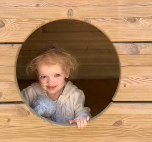 Florie looking out of a wooden play opening