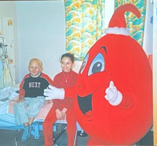 Luciano and sister sittin gon hospital bed with a red costume figure