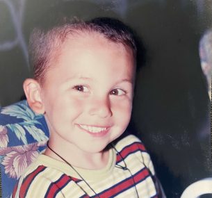 Luciano smiling wearing a red stripped tshirt