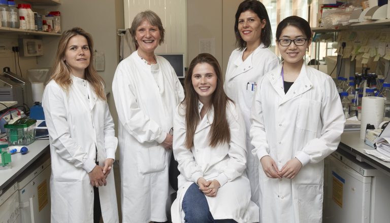 five female researchers wearing white lab coats