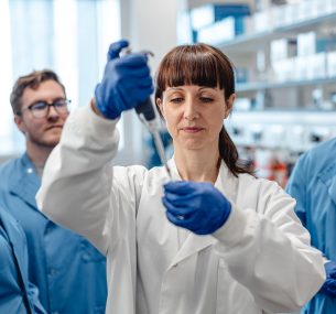 3 researchers watching female researchers with pipette min