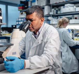 Researcher looking into a microscope