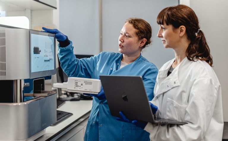 Two female researchers looking at a screen machine