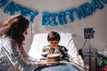 Billy milestones with happy birthday balloons on the wall and cake (1)