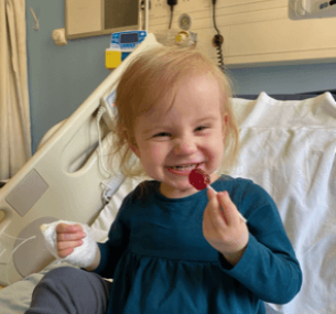 Florrie with lollipop in hospital bed