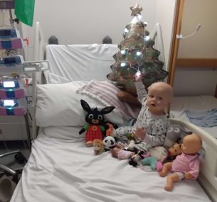 Lucy with Christmas tree in hospital bed