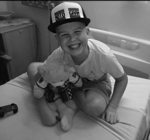 Micky smiling at camera with teddy bear