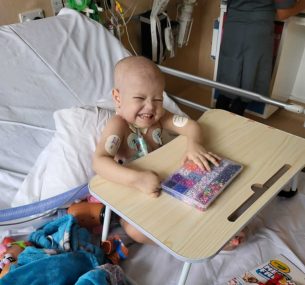 Archer smiling in hospital bed with beads