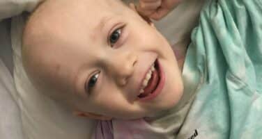 Jack in bed smiling with no hair