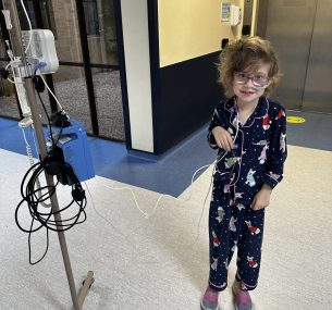 Dulcie stood in hospital smiling at the camera