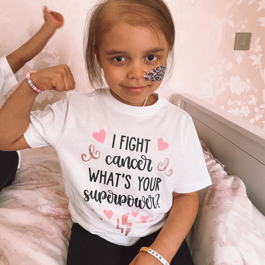 Arianna wearing an 'I fight cancer, what's your superpower?' t-shirt and smiling at the camera